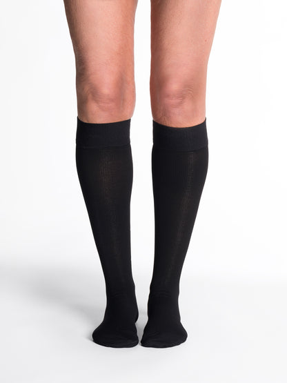 Woman wearing Sigvaris Women's Essential Cotton compression grip-top knee-highs in the color Black