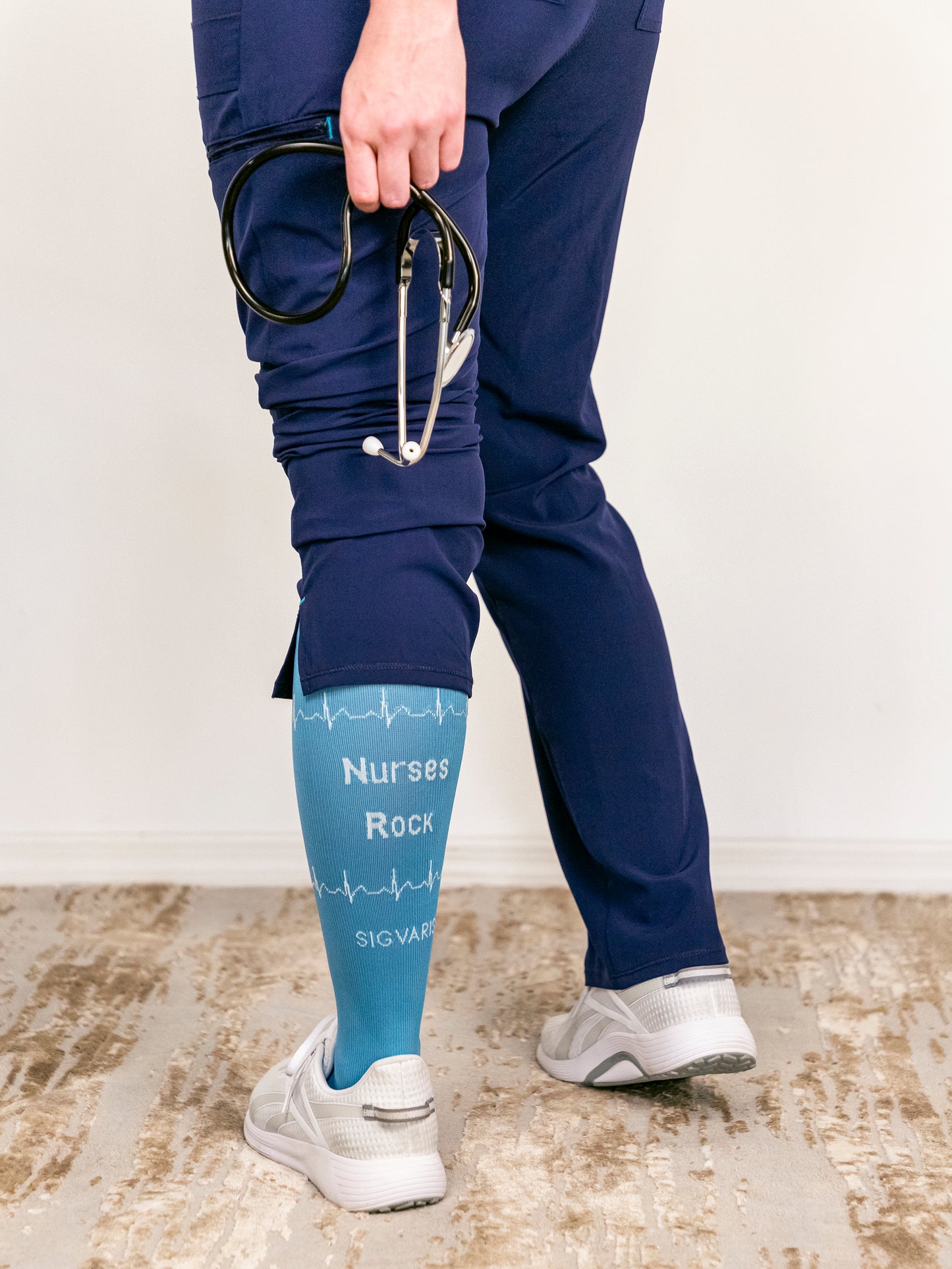 Nurse standing to show the back of Sigvaris Well-being Microfiber Shades compression socks in the color Nurse Blue