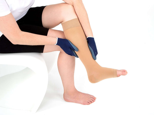 Woman using Sigvaris Textile Gloves donning gloves to adjust compression stocking on her leg