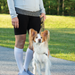 Woman wearing Sigvaris Essential Cotton compression socks, standing in a park with a Papillon dog