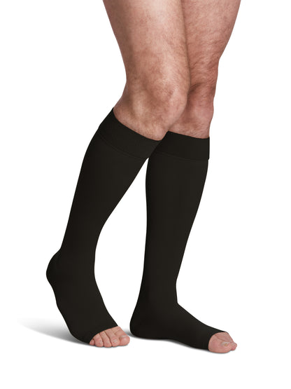 Man wearing Sigvaris Men's Essential Opaque open-toe compression stockings with grip-top in plus size  in the color Black