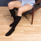 Man getting dressed, sitting in a chair and wearing Sigvaris Essential Opaque compression socks